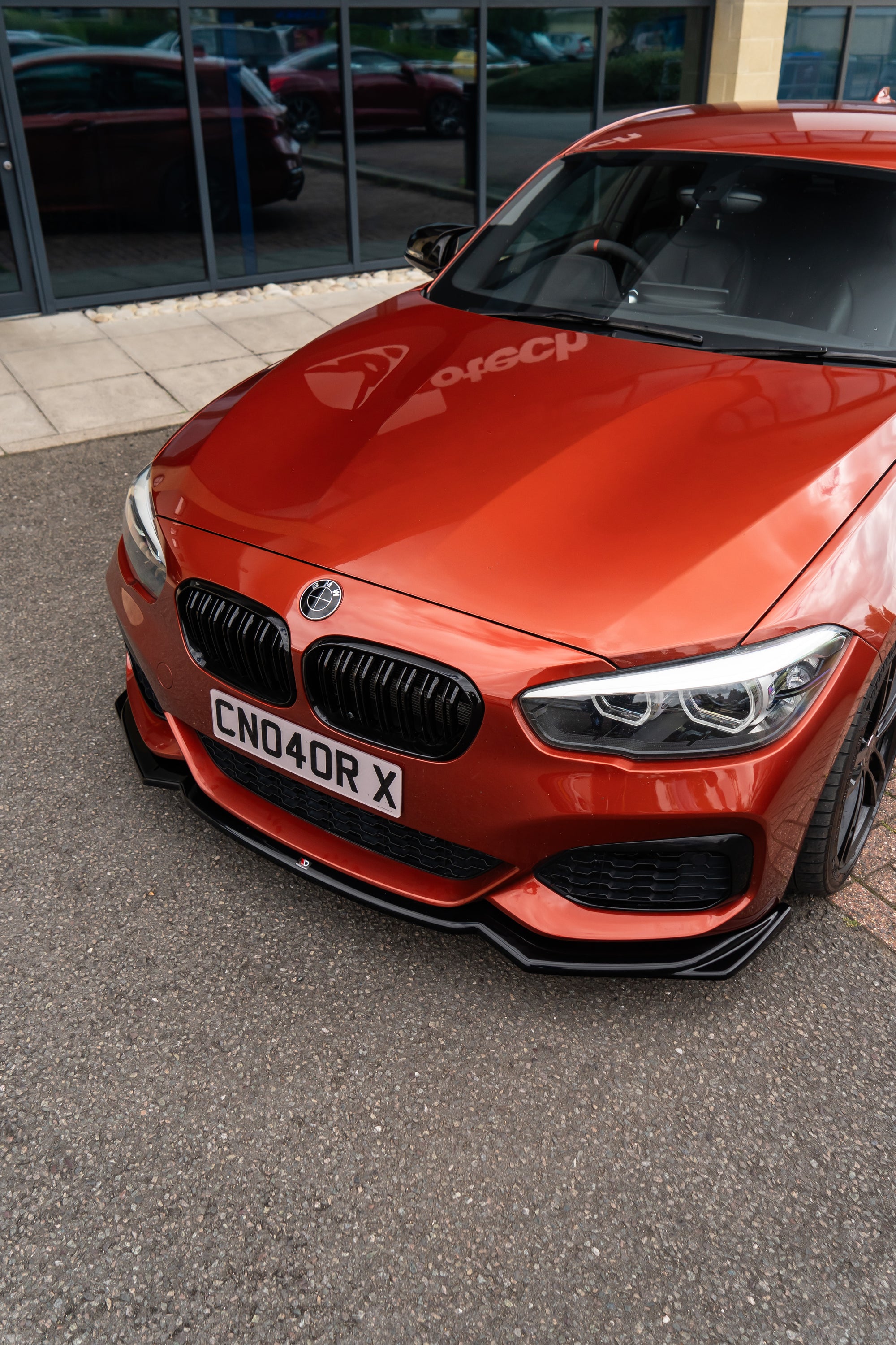 Red BMW with an aftermarket maxton front splitter attached.