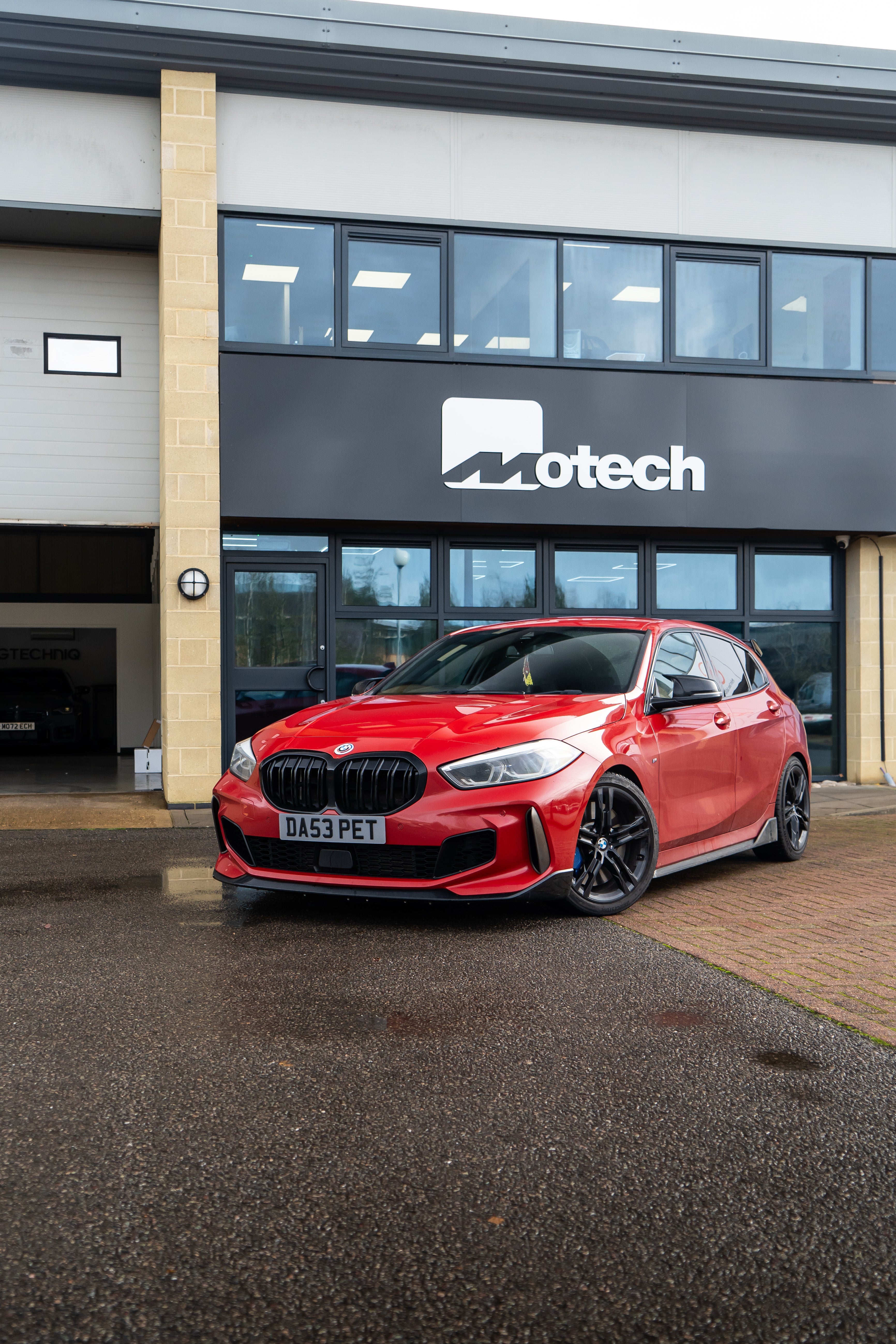 Red 1 Series on Motech Stance Springs parked outside a building with 'Motech' branding. 