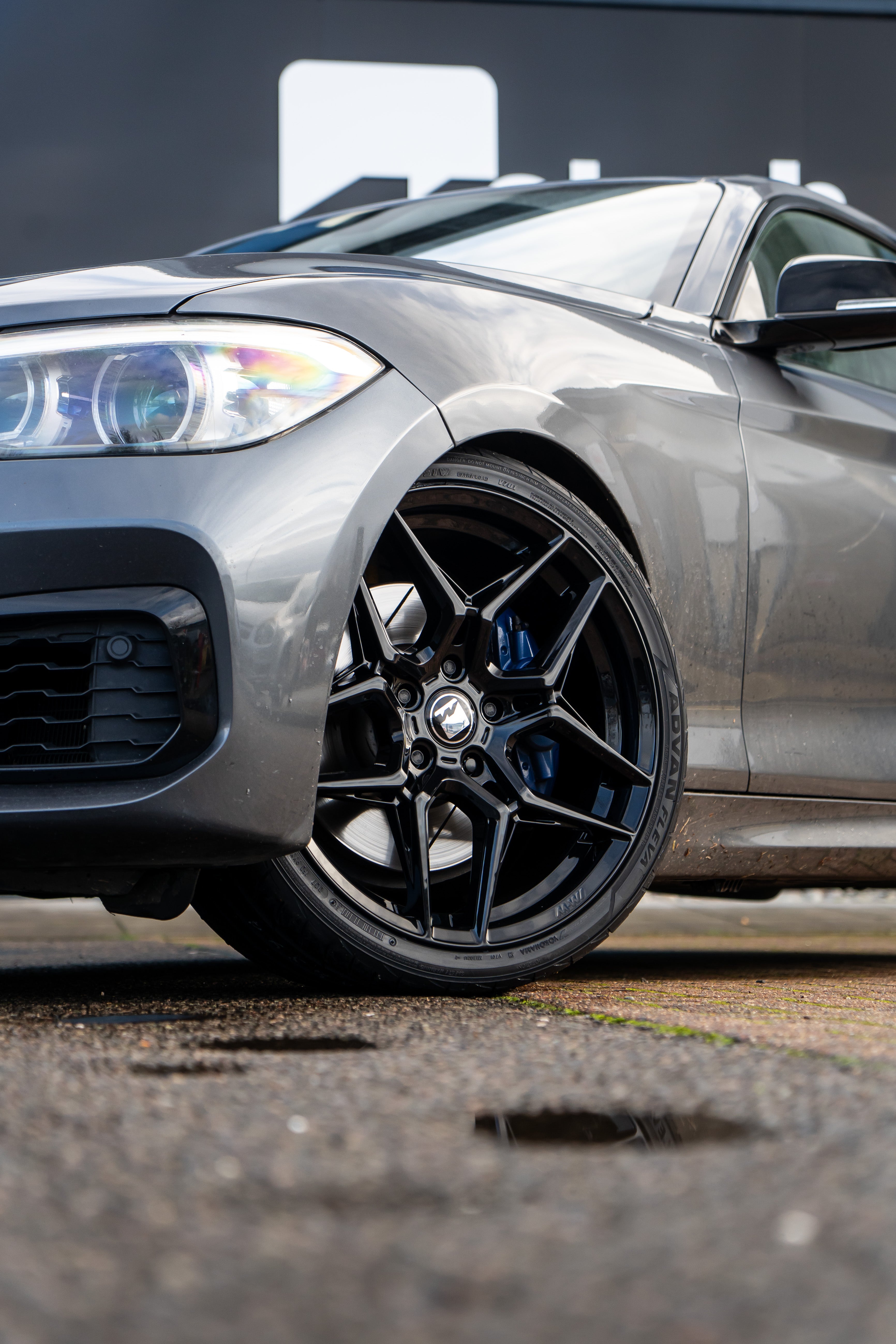 Close-up of a Precision Black M-W1 wheel on a grey BMW.