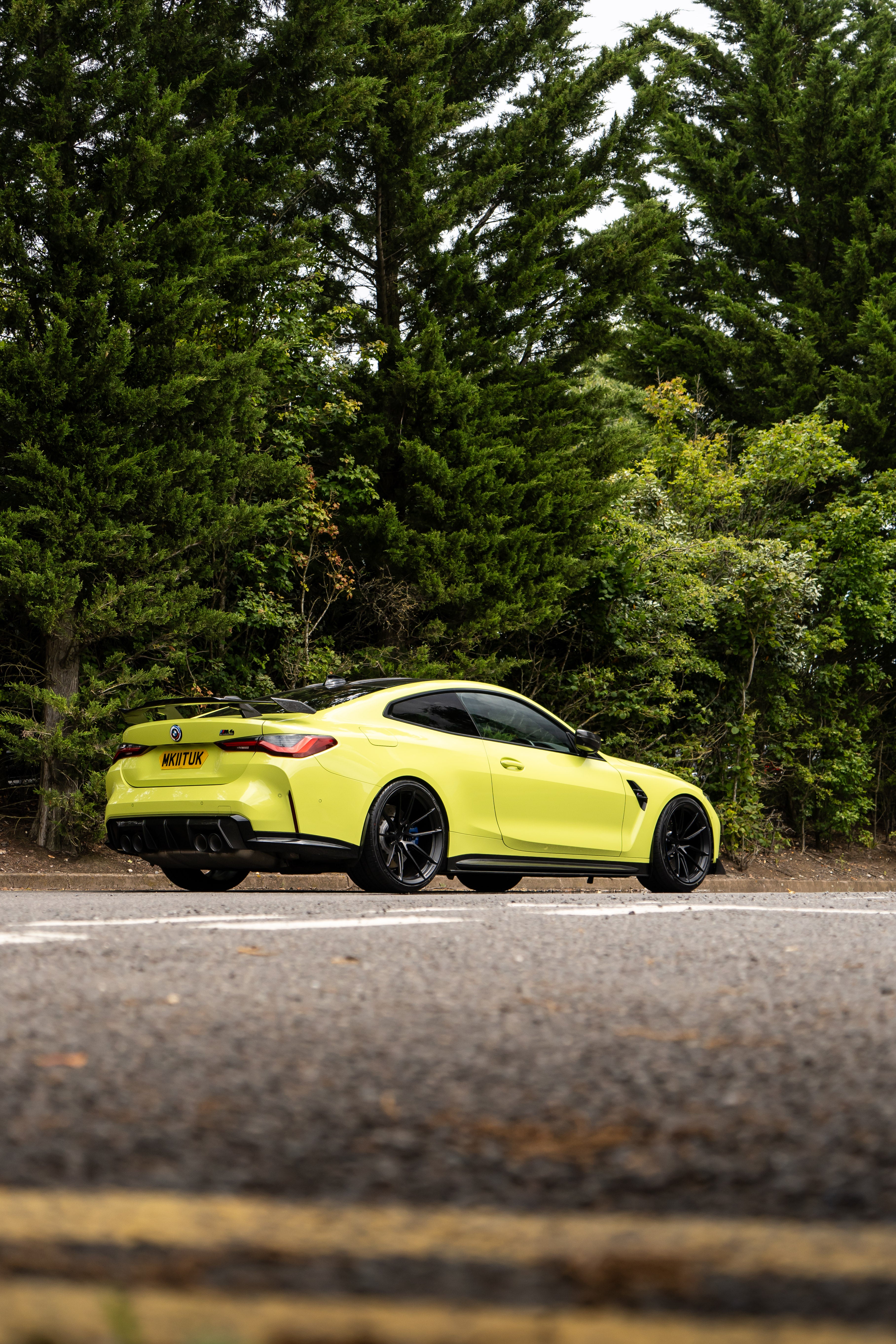 São Paulo Yellow BMW M4 on Motech Stance Springs parked in front of some trees. 