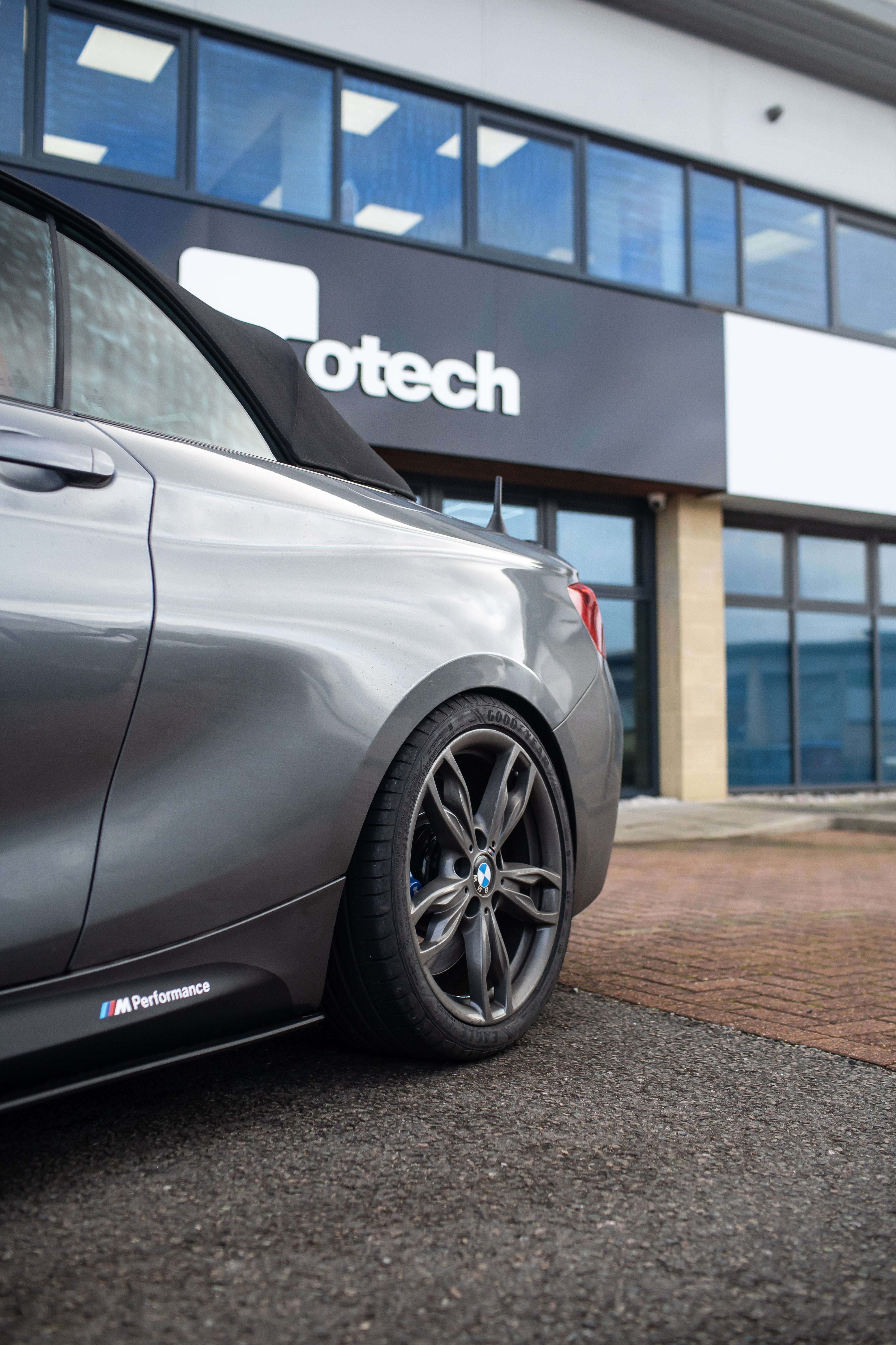 Back wheel of a BMW 2 Series on Motech Stance Springs parked outside the Motech building.