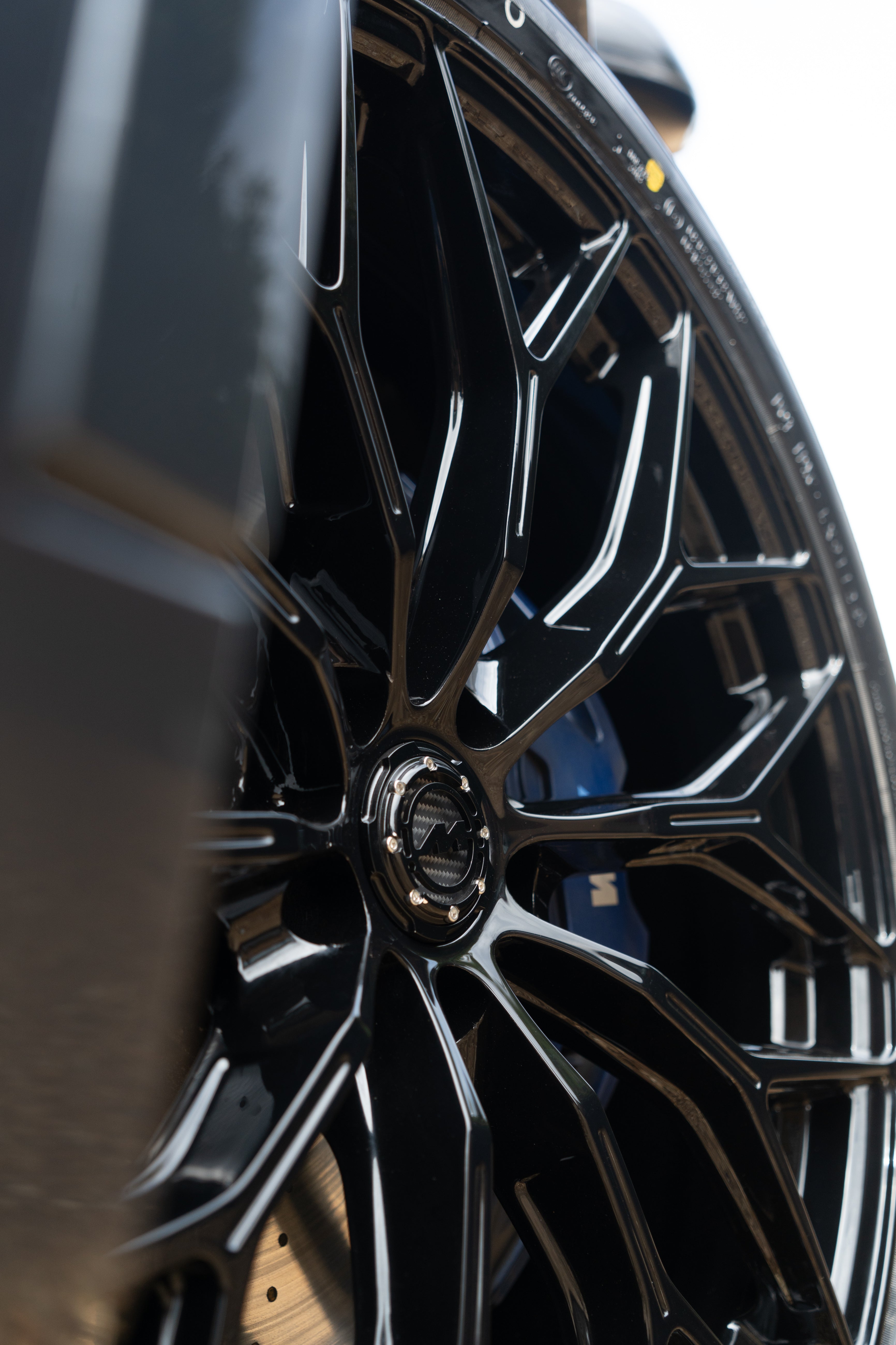 Close-up of a black Motech M-WX wheel with a black Motech centre-cap and a blurred background.