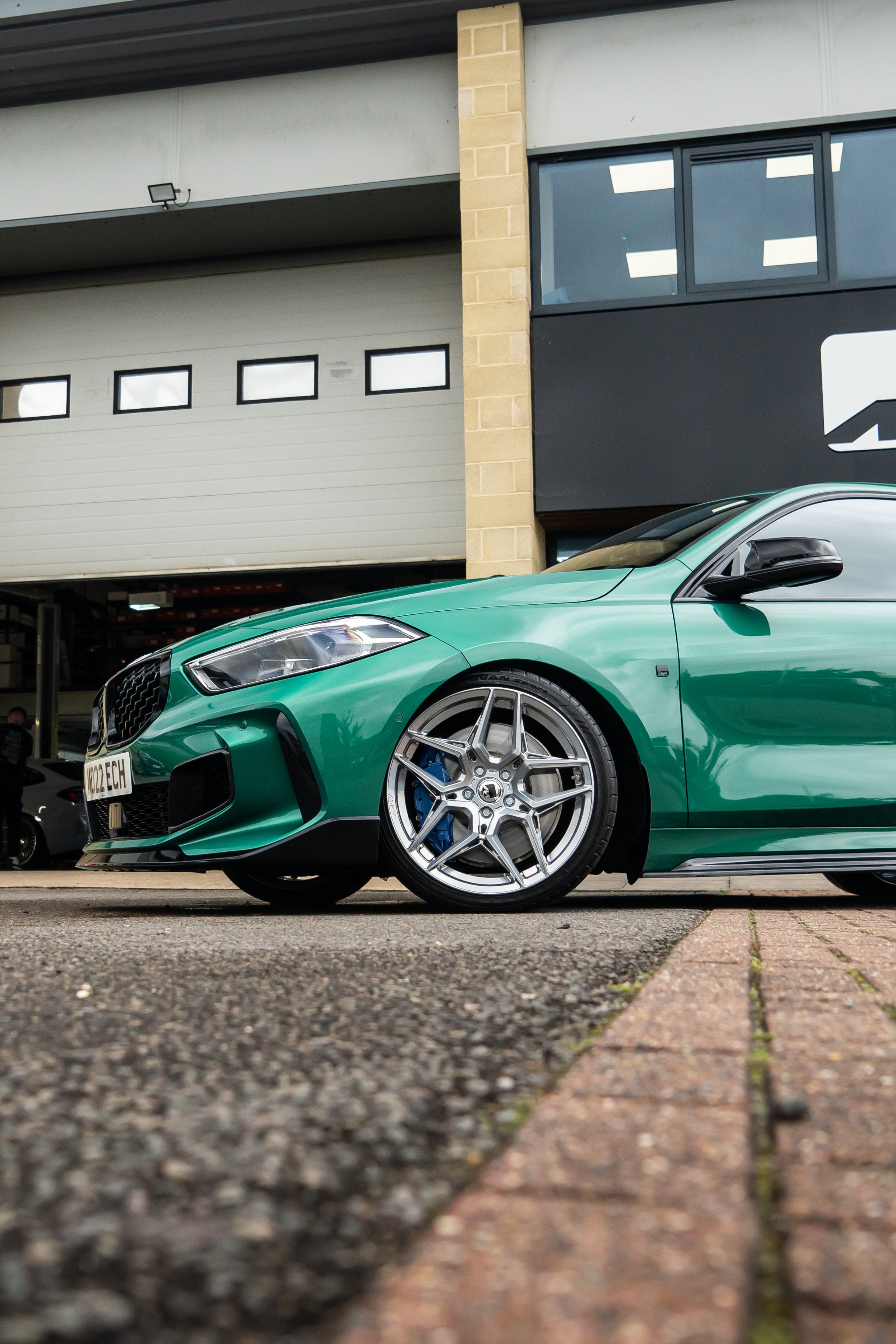 Front Green 1 Series on Motech Stance springs parked outside a building on a red brick street.