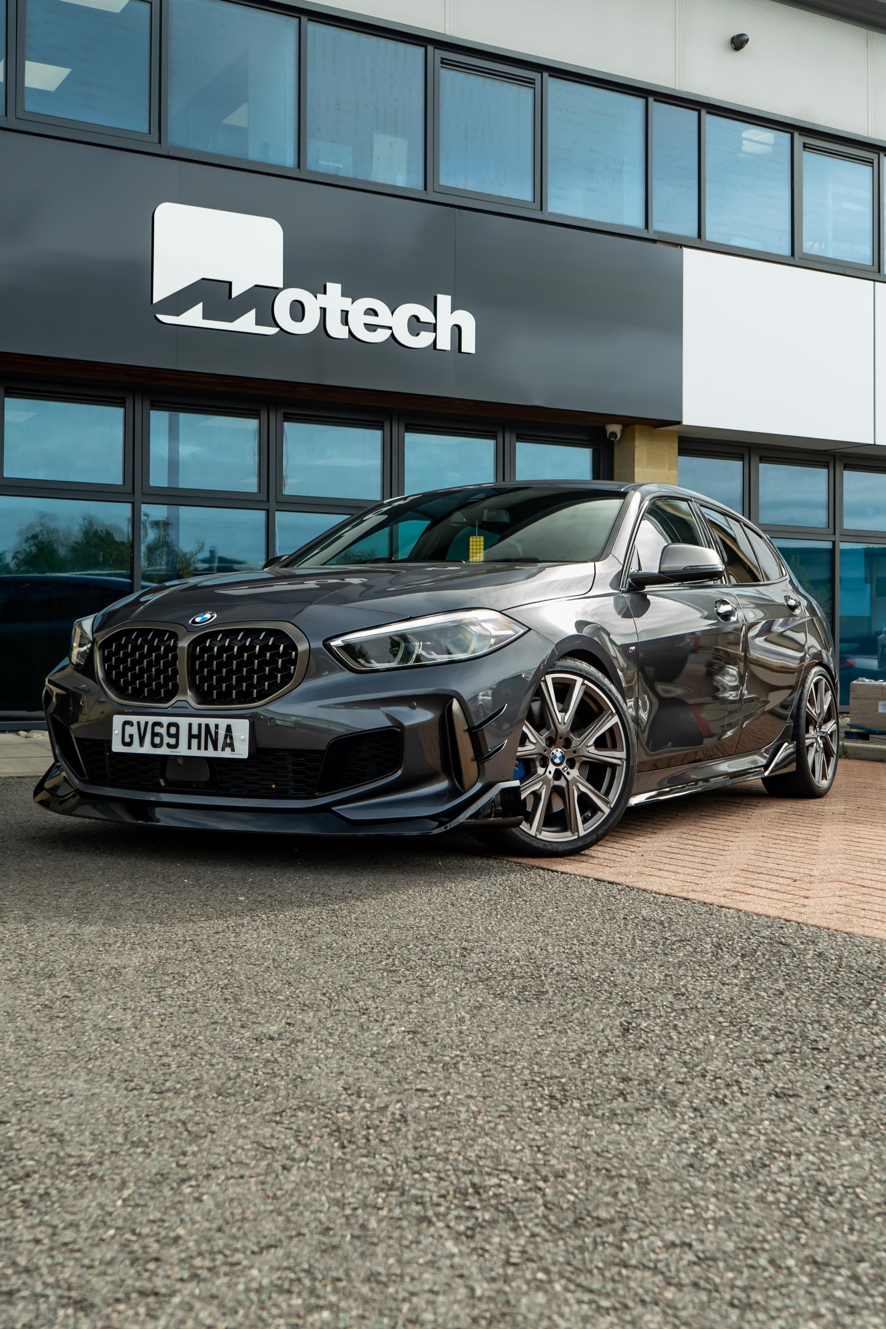 Grey BMW car parked in front of a building with Motech branding.
