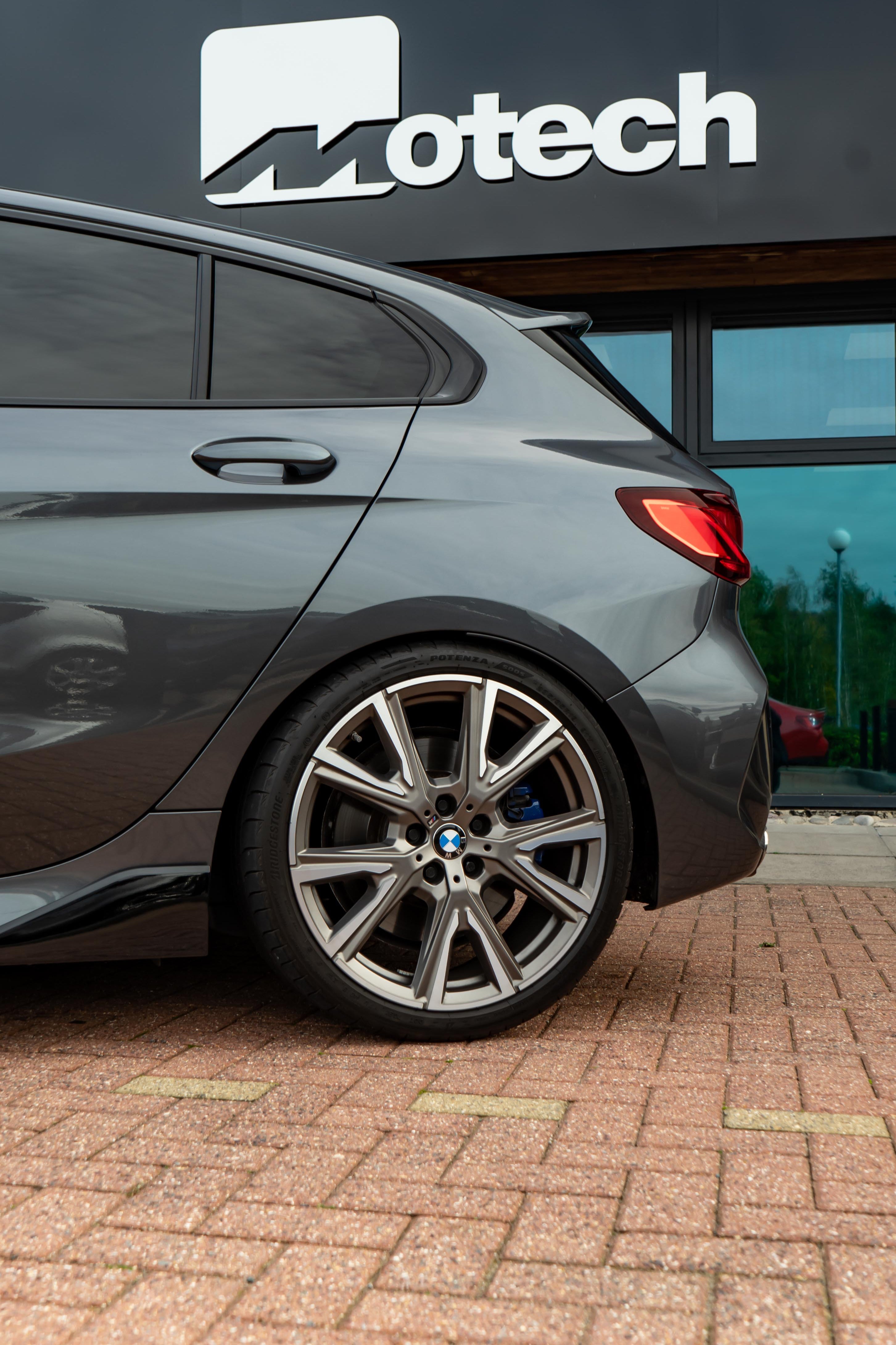Gray car parked in front of a building with 'Motech' branding.